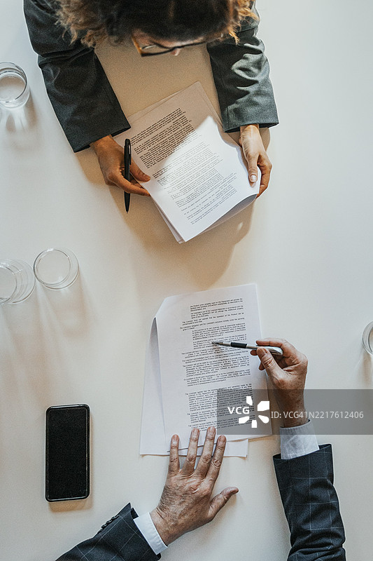 男性和女性商务专业人士在办公室查看文件的俯视图图片素材