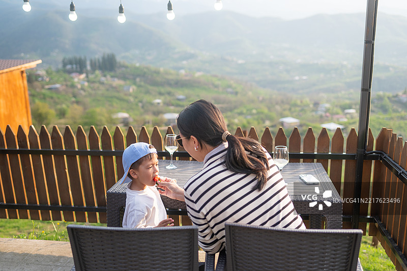 温柔的妈妈在户外喂孩子吃草莓图片素材