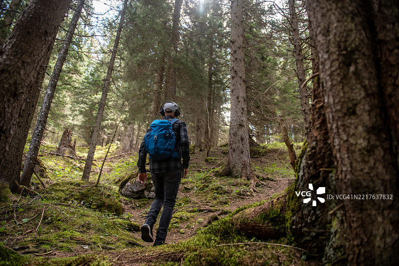 在森林中徒步旅行的男子，听着复古的卡带随身听图片素材