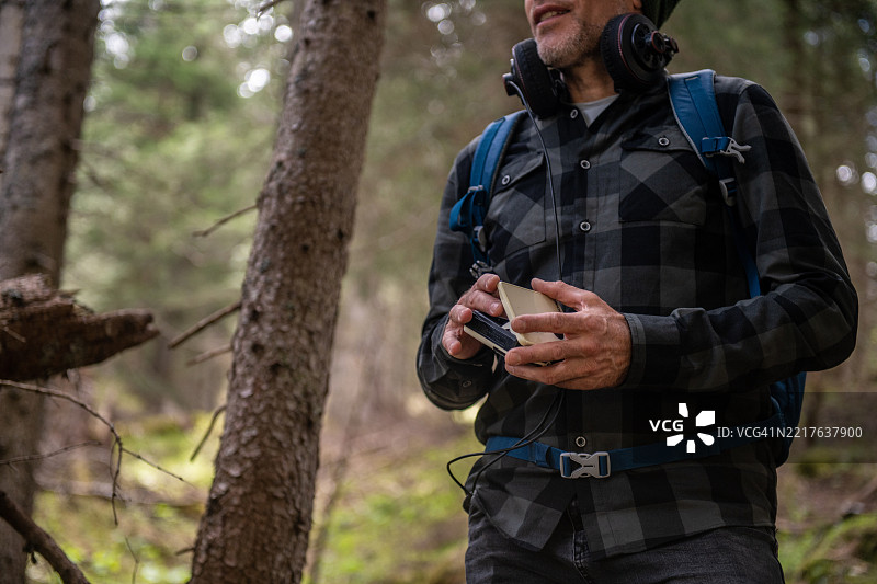 在森林中徒步旅行并听着复古卡带随身听的男人图片素材