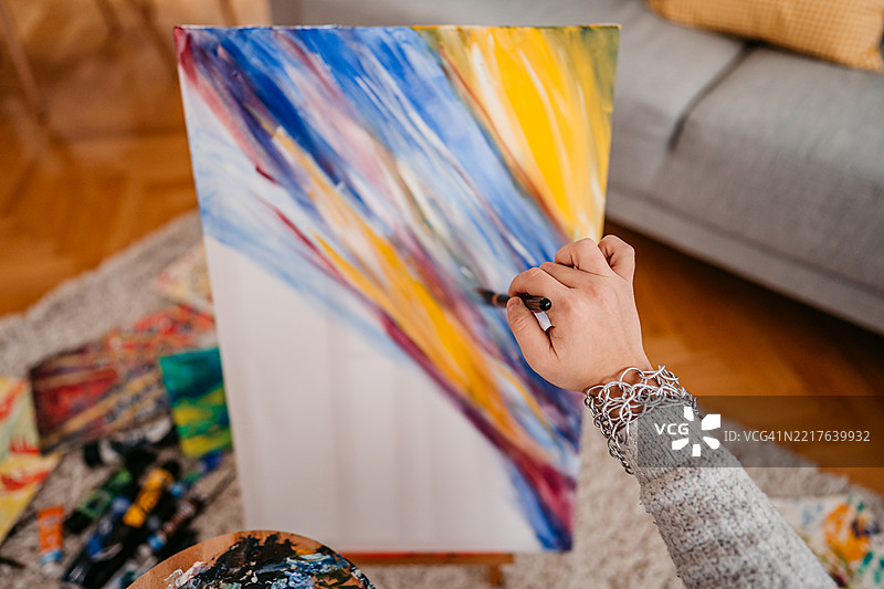 年轻女性艺术家坐在家中地板上画画图片素材