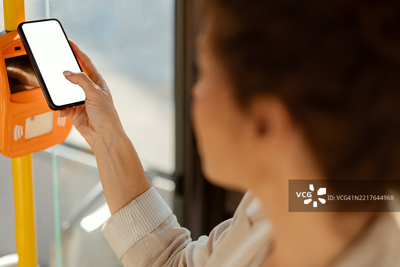 现代通勤者在公交站用智能手机进行无接触支付图片素材