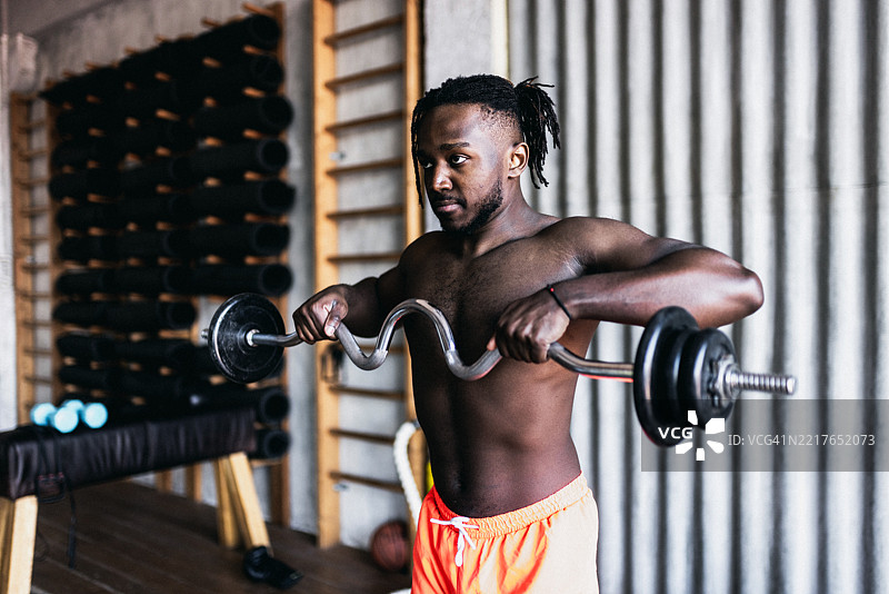 强壮的男人在健身房举起杠铃，展现出决心和健康。图片素材