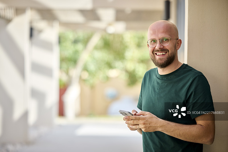 快乐的商人在走廊里拿着智能手机图片素材