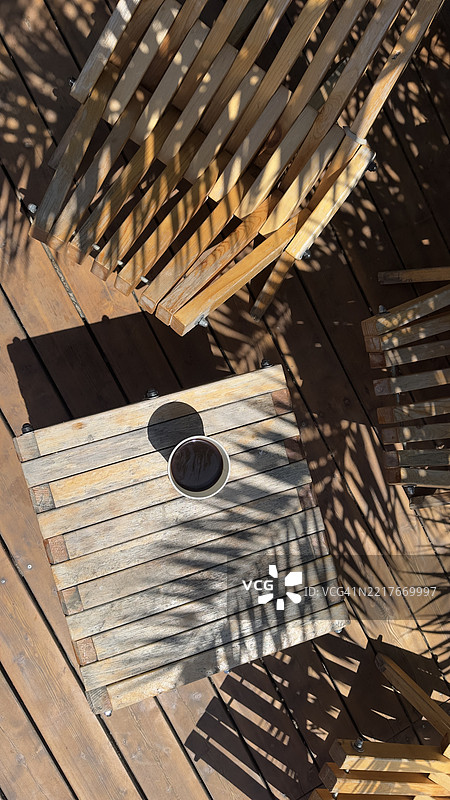 户外木质甲板上有桌子、咖啡杯和椅子的阴影图片素材