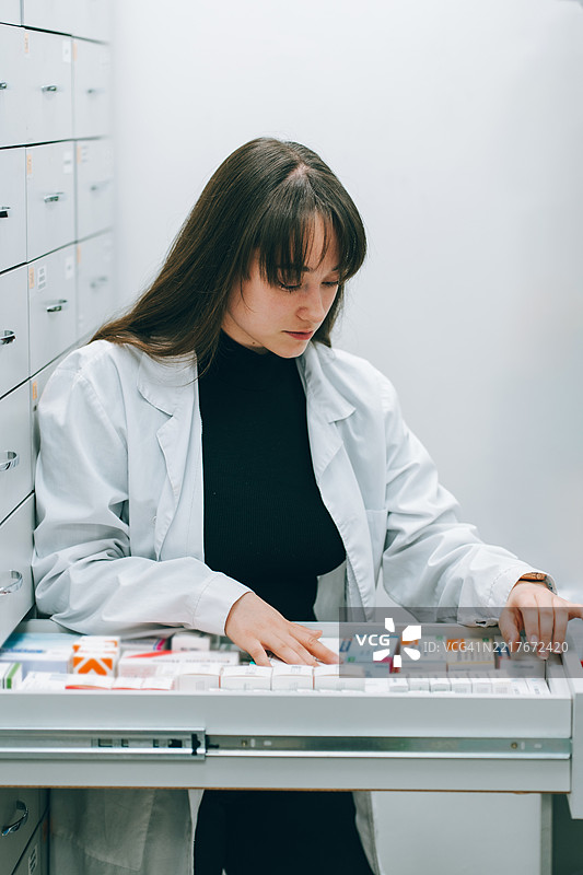 年轻药剂师在药房抽屉中寻找药物图片素材