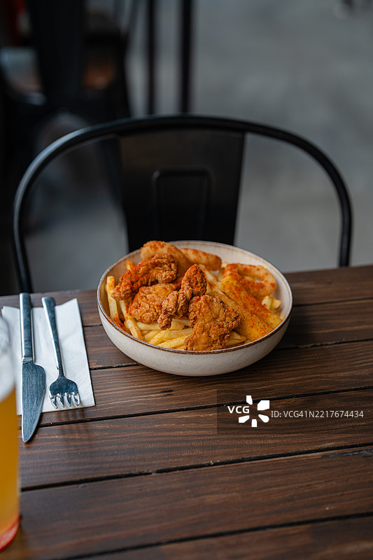 脆皮炸鸡条和调味薯条放在木桌上的碗里图片素材