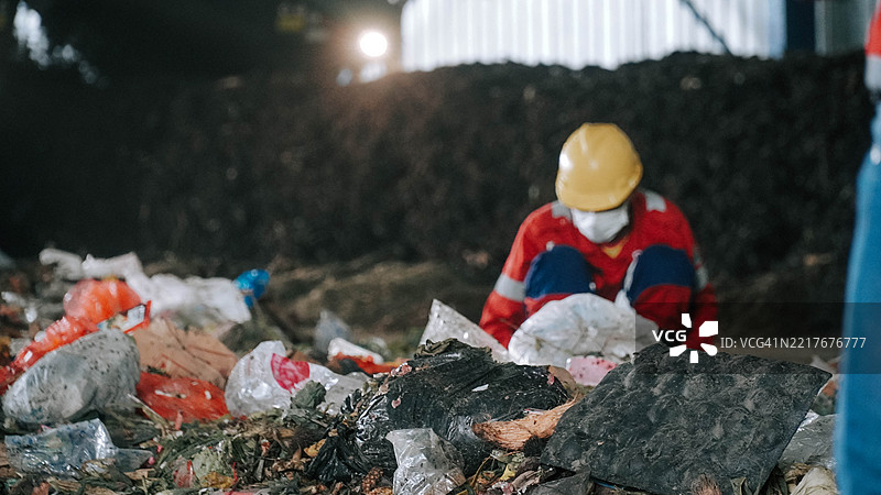 印度尼西亚马朗，2025年1月18日，戴着口罩的男子坐在垃圾堆中图片素材