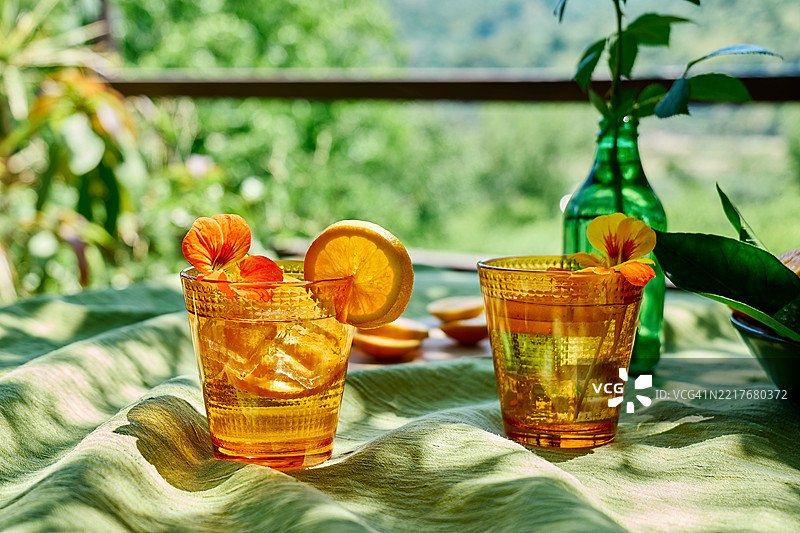 花园桌子上的冰镇花草水，加入了可食用的金莲花和橙片。清爽的夏季饮品。健康的有机排毒苏打饮料。图片素材