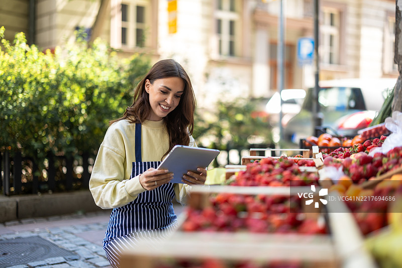 光彩照人的女性在她的水果店监督日常运营图片素材