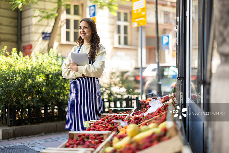 面带愉悦的女性向顾客提供新鲜水果图片素材