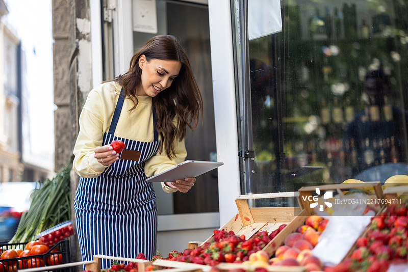 美丽的女销售员在市场上检查水果展示图片素材