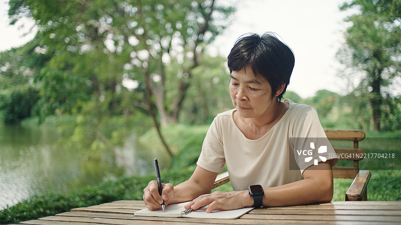 成熟的女性在大自然中写作。图片素材