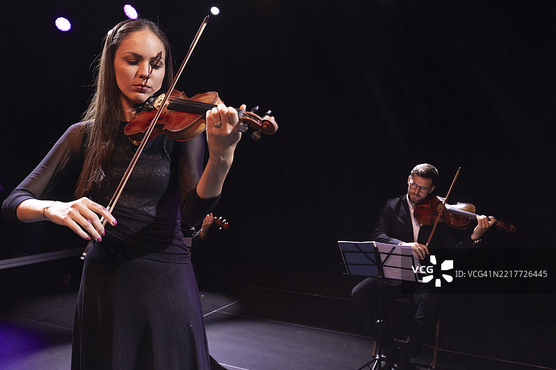 女小提琴手在剧院舞台上激情演奏，指挥一场古典音乐会图片素材