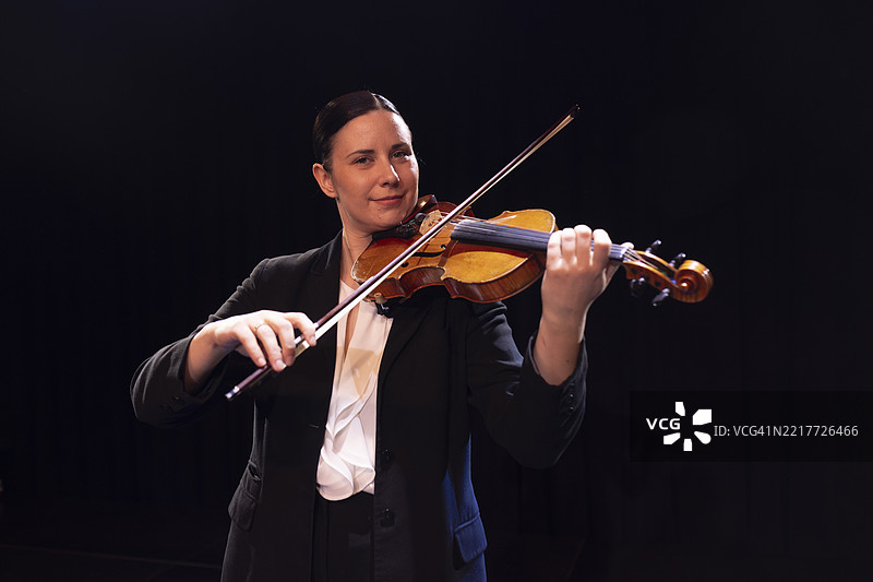女性小提琴家在古典音乐会上演奏小提琴的肖像图片素材