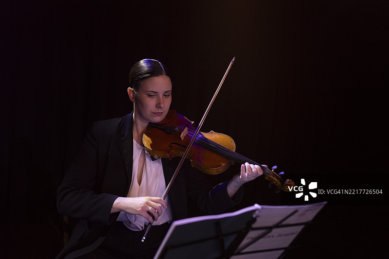 一位女性小提琴手在古典音乐会上演奏小提琴的肖像图片素材