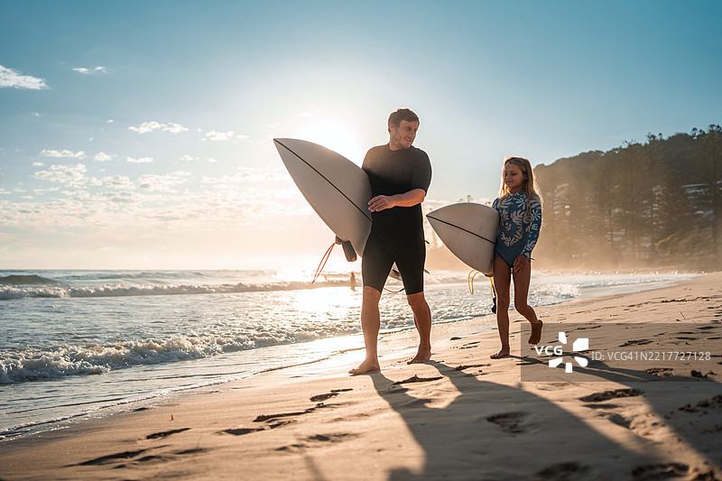 白人父女在日出时快乐地携带冲浪板散步图片素材