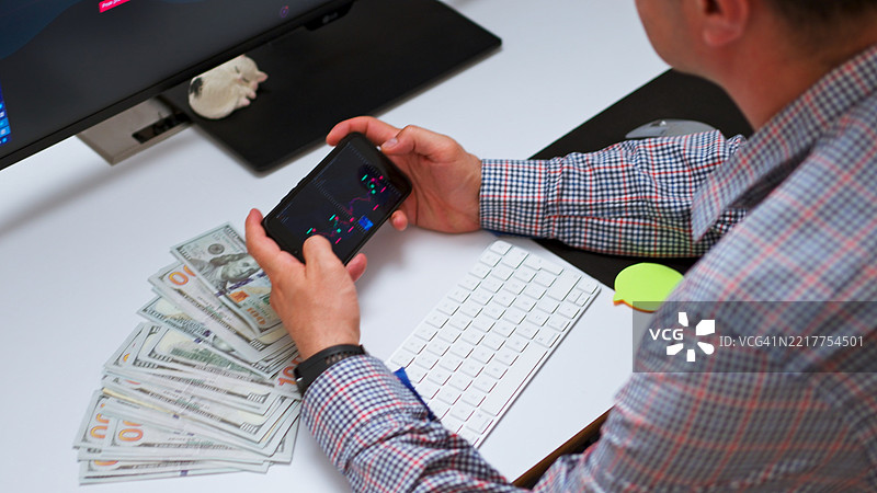 在家中使用大屏幕和手机分析加密货币或股票市场趋势图片素材