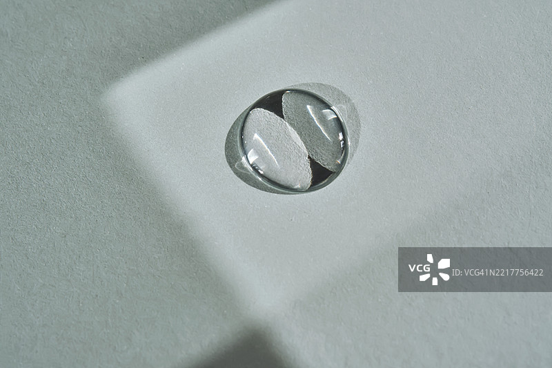 蓝色背景上的一滴微米水或精华液。图片素材