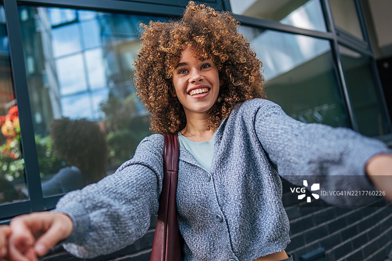 年轻女性微笑着伸出手拍自拍图片素材