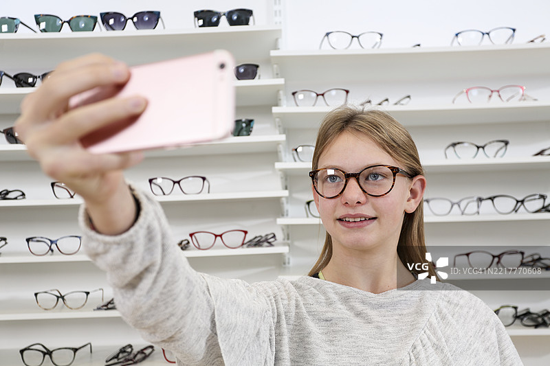 微笑的女孩在眼镜店里自拍新眼镜图片素材