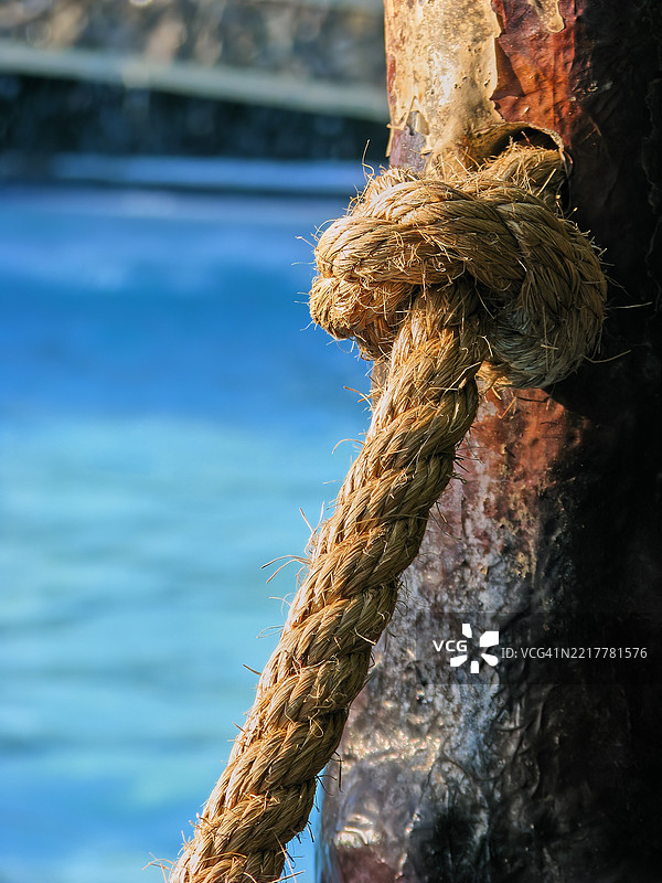 一根粗厚的绳索缠绕在一根风化的生锈柱子上。图片素材