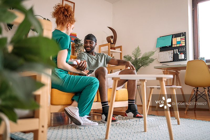 年轻女护士在患者家中客厅测量血压，面露积极情绪图片素材