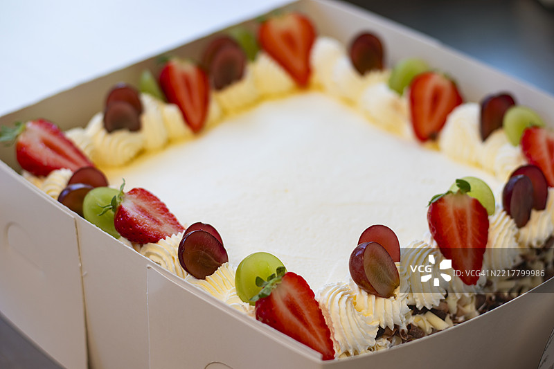 白色奶油蛋糕，上面装饰有新鲜水果，放在盒子里，中间留有空间写信息图片素材