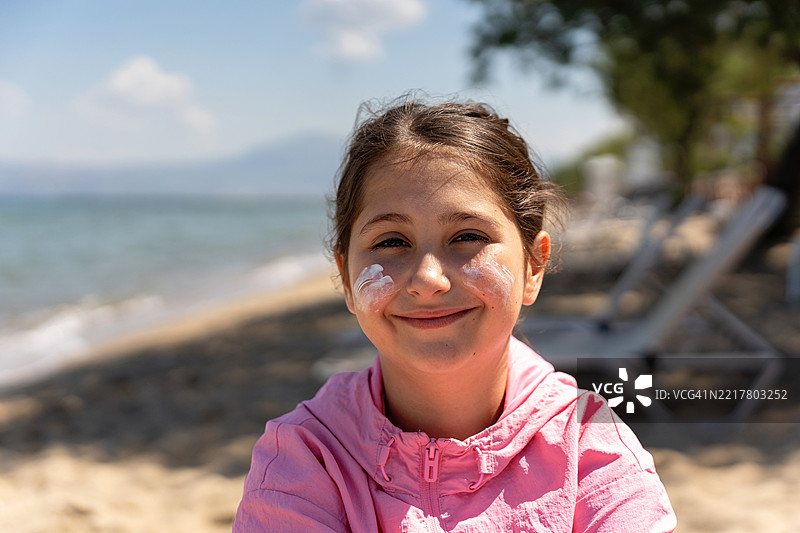 年轻女孩在阳光明媚的海滩上微笑，享受户外度假时光图片素材