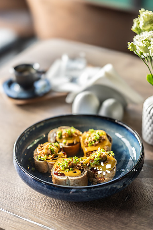 餐厅桌子上的早餐菜肴：用奶酪酱和细香葱准备的吐司三明治，放在碗里。图片素材