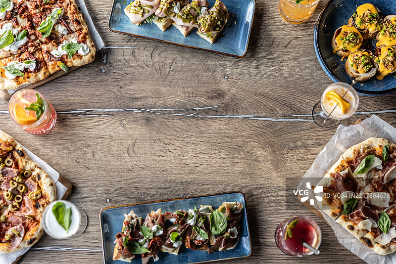 餐厅桌子上的各种食物俯视图，包括比萨、佛卡夏、吐司面包和饮料图片素材