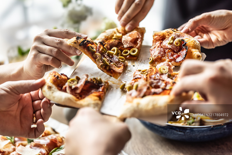 一群朋友在一起享用来自比萨店的披萨午餐图片素材