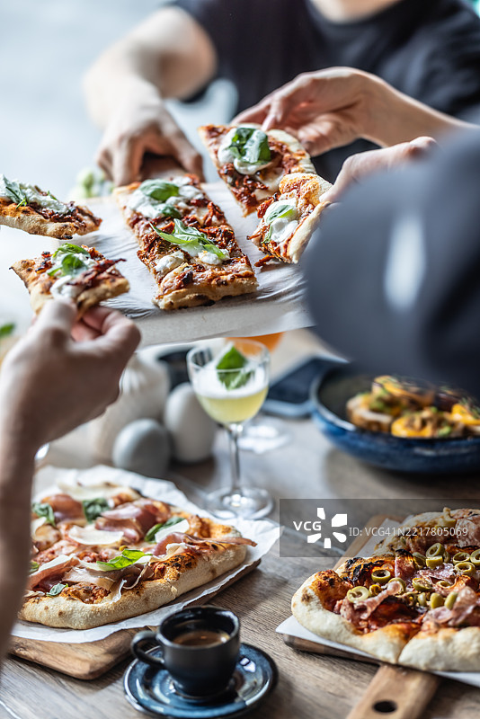 一群朋友在一起享用来自比萨店的比萨饼午餐图片素材
