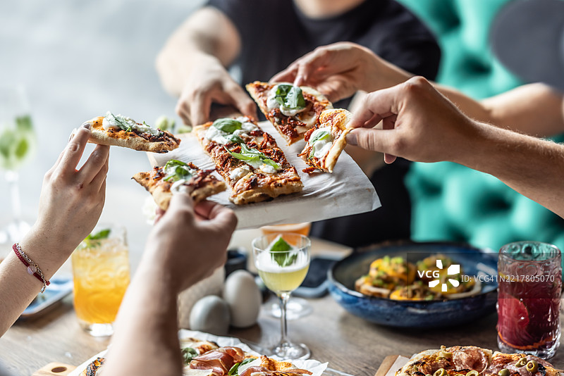 一群朋友在一起享用来自比萨店的披萨午餐图片素材