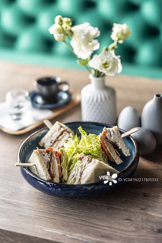 餐厅里的盘子上摆放着烤面包、鸡肉培根和生菜，作为早餐菜肴。图片素材