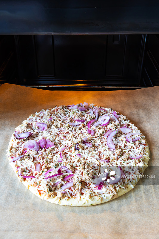 冷冻披萨上放着金枪鱼，放在烤箱的烤盘上图片素材