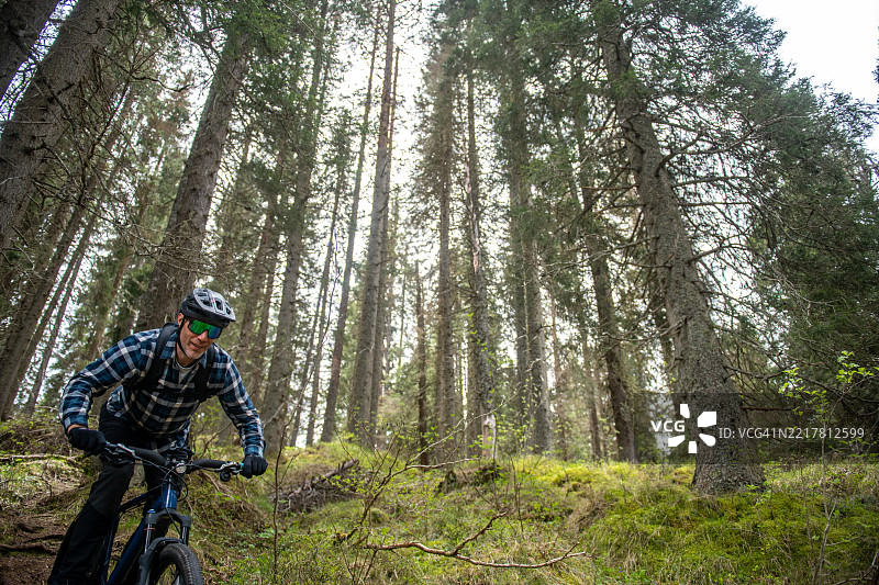 男子在森林自行车道上骑山地车图片素材