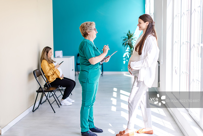 孕妇在明亮的医院候诊区接受产前护理咨询图片素材