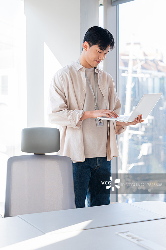 年轻人在办公室专注于笔记本电脑工作图片素材