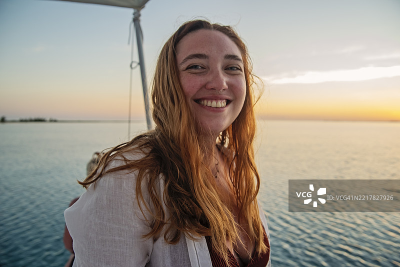 日落时分，身材积极的年轻女性在船上合影。图片素材