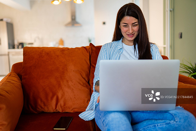 女人在家沙发上使用笔记本电脑图片素材
