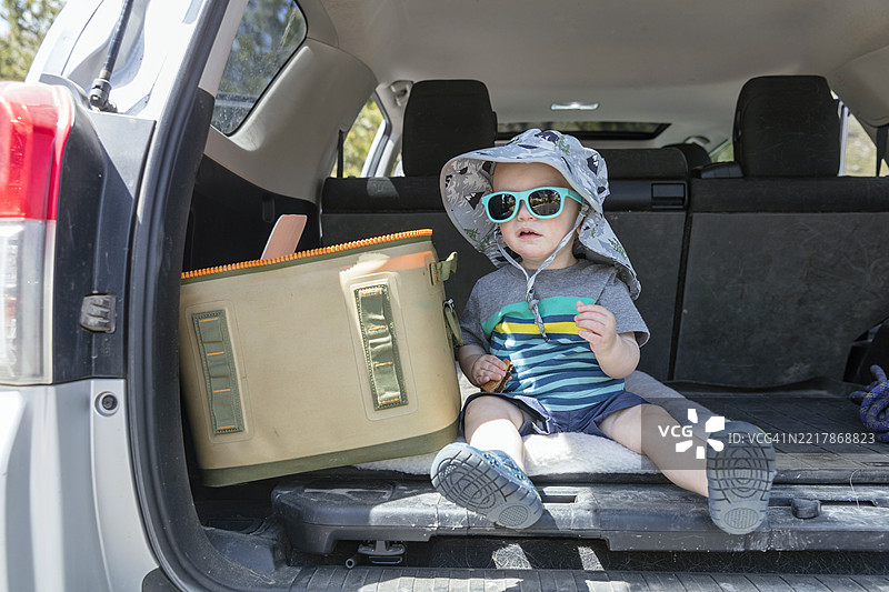 一个小男孩在SUV的后面玩耍图片素材