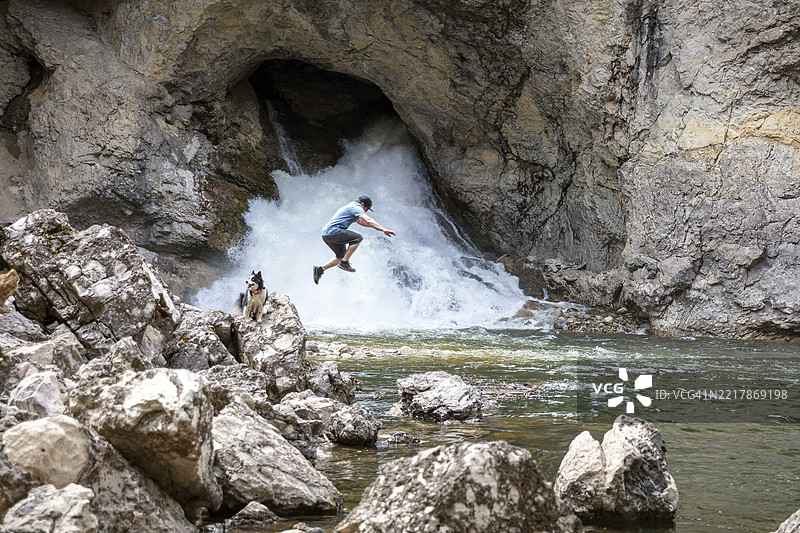 一名年轻男子在风景如画的瀑布附近的岩石海岸徒步旅行图片素材