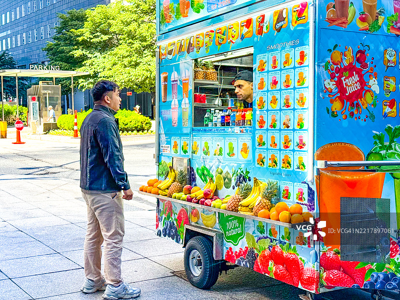 男子在纽约市的食品亭选择冰沙图片素材