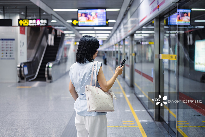 年轻城市女性在地铁站台等候地铁的背影图片素材