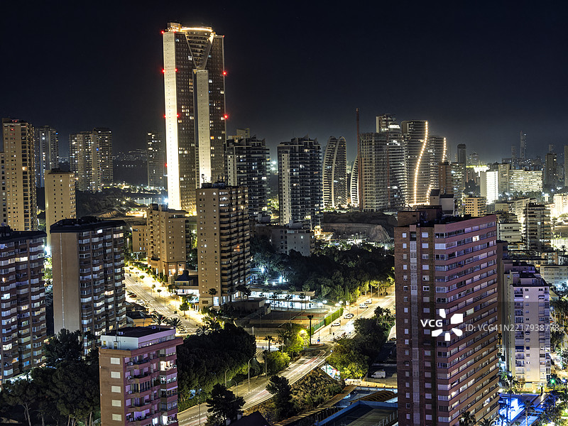 现代城市的高空视角，夜晚大型摩天大楼灯火辉煌。西班牙贝尼多姆市。图片素材