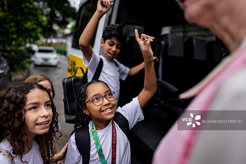 兴奋的学生在校车到达时与老师交谈图片素材