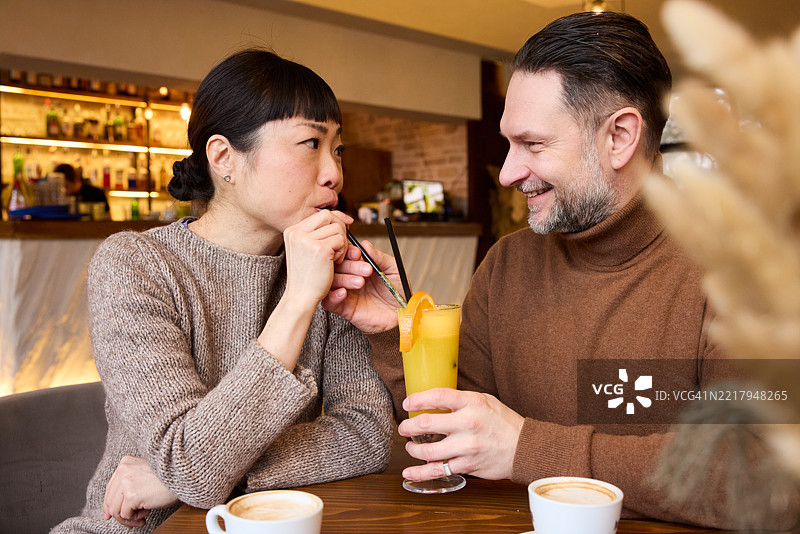 跨种族情侣在咖啡馆分享橙汁。图片素材