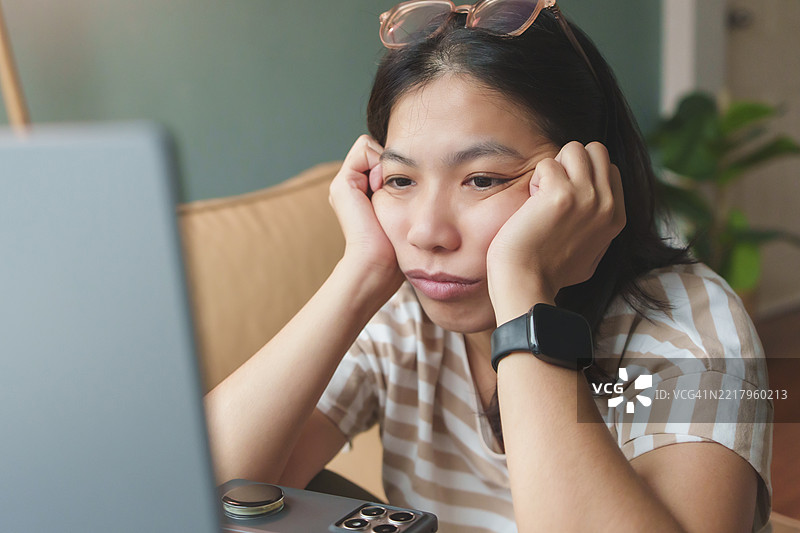 亚洲女性在家办公时感到压力和疲惫。图片素材
