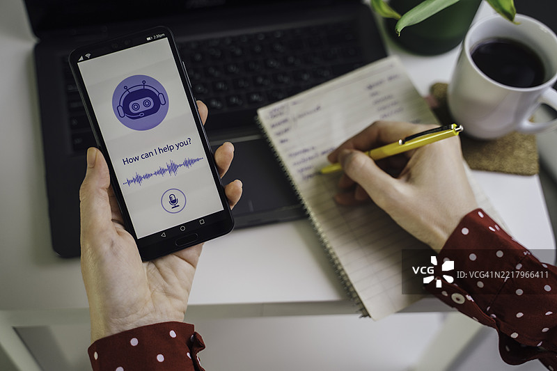 专注的工作人员使用智能手机并做笔记图片素材